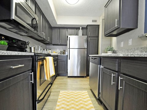 a kitchen with black cabinets and a stainless steel refrigerator