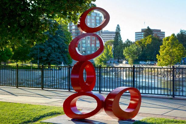 a sculpture of red circles in front of a body of water