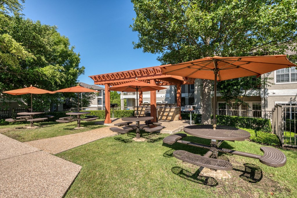 a picnic area with tables and umbrellas in front of a building