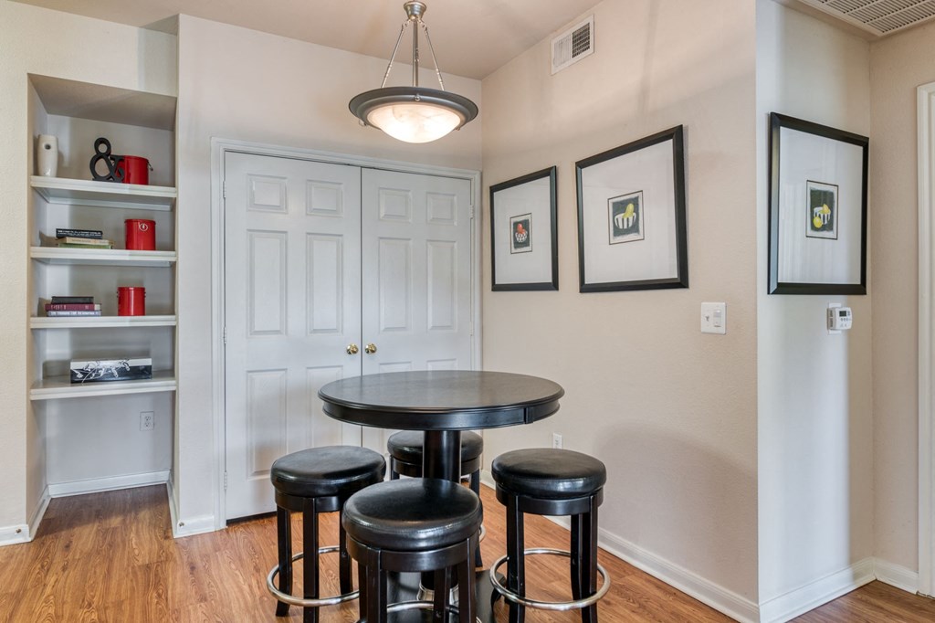a dining room with a table and three stools in front of a white door