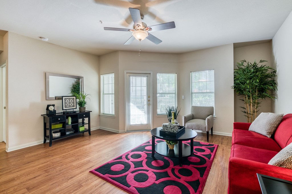 a living room with a red couch and a ceiling fan
