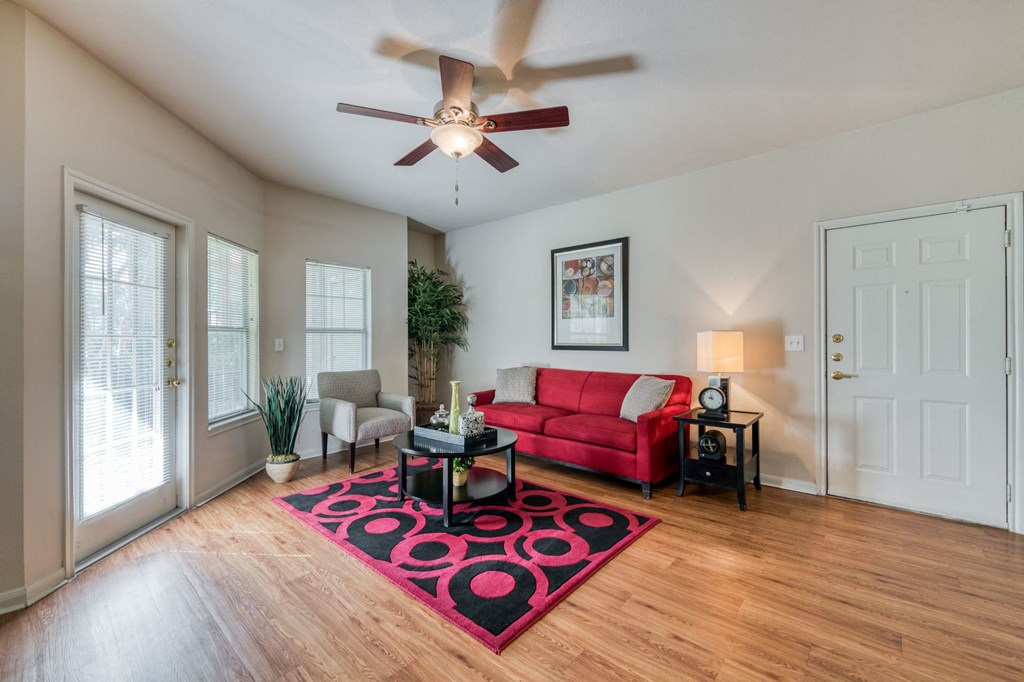 a living room with a red couch and a ceiling fan