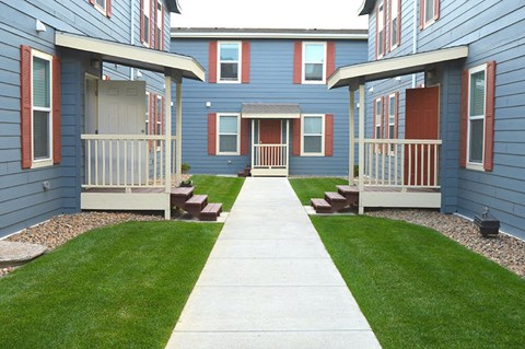 a sidewalk in front of a row of blue houses