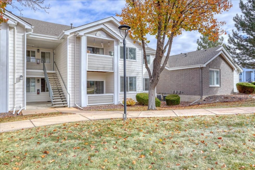 the front of a white house with a tree and a sidewalk
