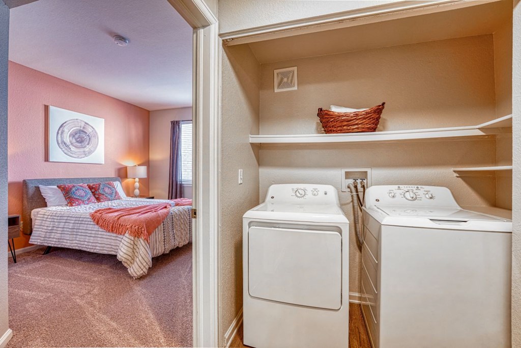 a laundry room with a bed and a washer and dryer in a bedroom
