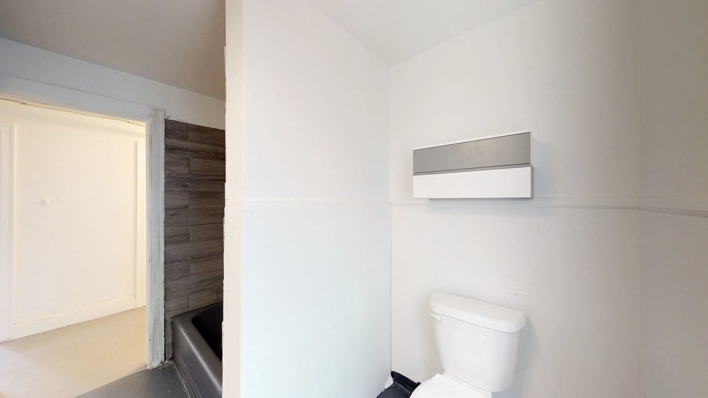 a white bathroom with a toilet and a window