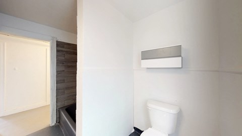 a white bathroom with a toilet and a window