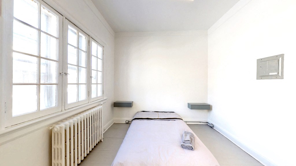 a bedroom with a bed and a radiator and large windows