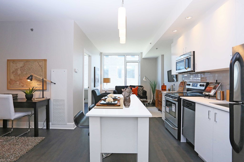 a kitchen and living room with a white counter top and appliances
