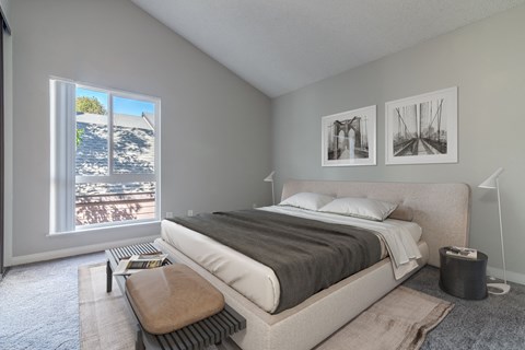 A bedroom with a large bed and a view of the beach through the window.