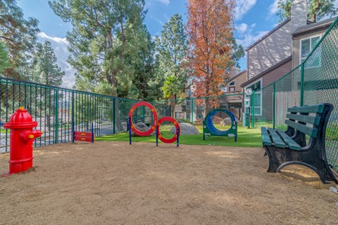 A playground with a red fire hydrant, a green bench, and a red and blue play structure.