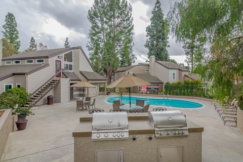 A backyard with a pool, grill, and patio furniture.