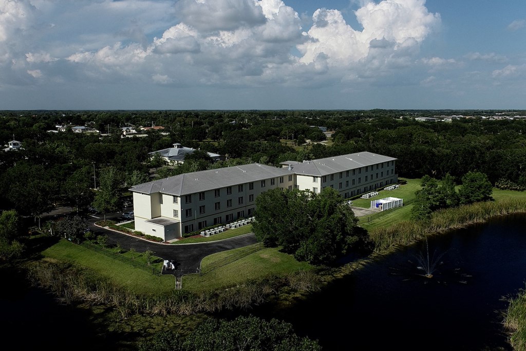 Villa Vincente Senior Apartments in For Myers, FL surrounded by trees beside water