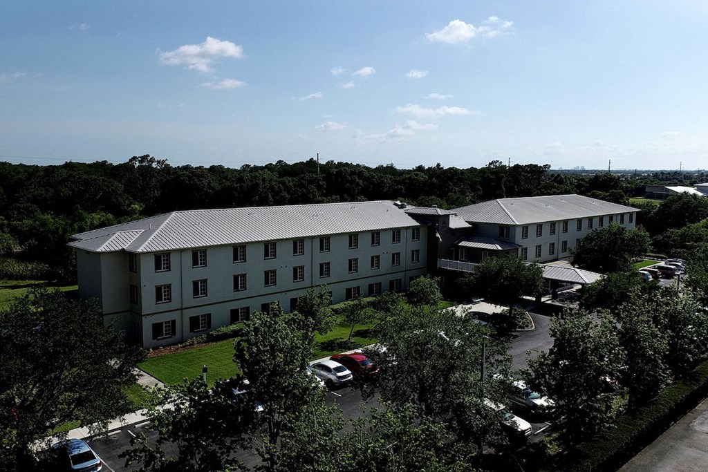 Villa Vincente Senior Apartments in For Myers, FL surrounded by trees beside water