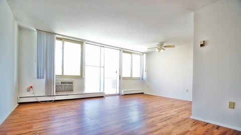 an empty living room with wood floors and a ceiling fan