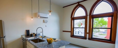 a kitchen with large arched windows and a granite counter top
