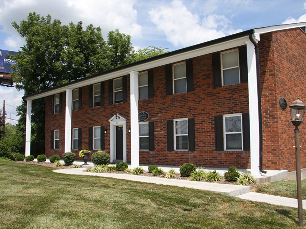 a red brick building with white columns and a lawn