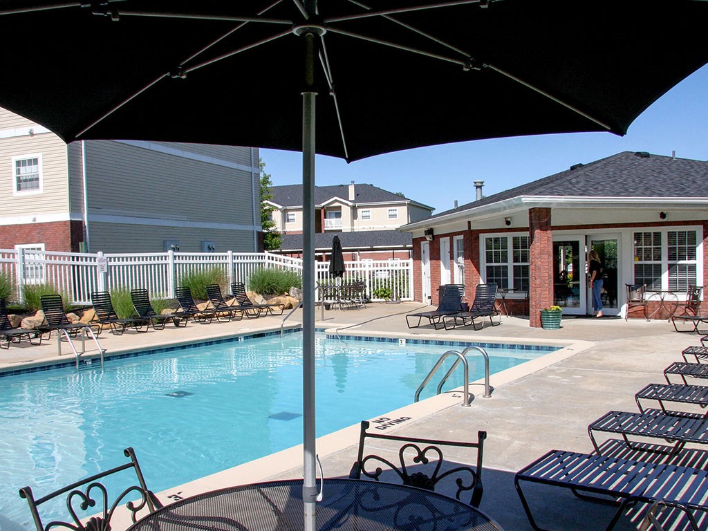 a swimming pool with chairs and umbrellas next to a building