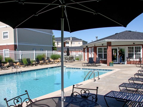a swimming pool with chairs and umbrellas next to a building