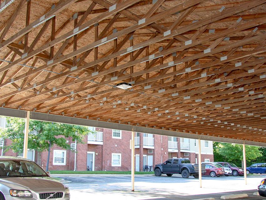 a covered parking lot with cars parked under a wooden roof