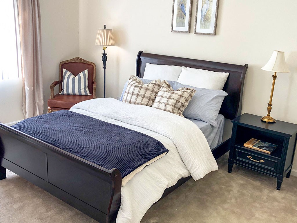 a bedroom with a bed and a chair and a night stand