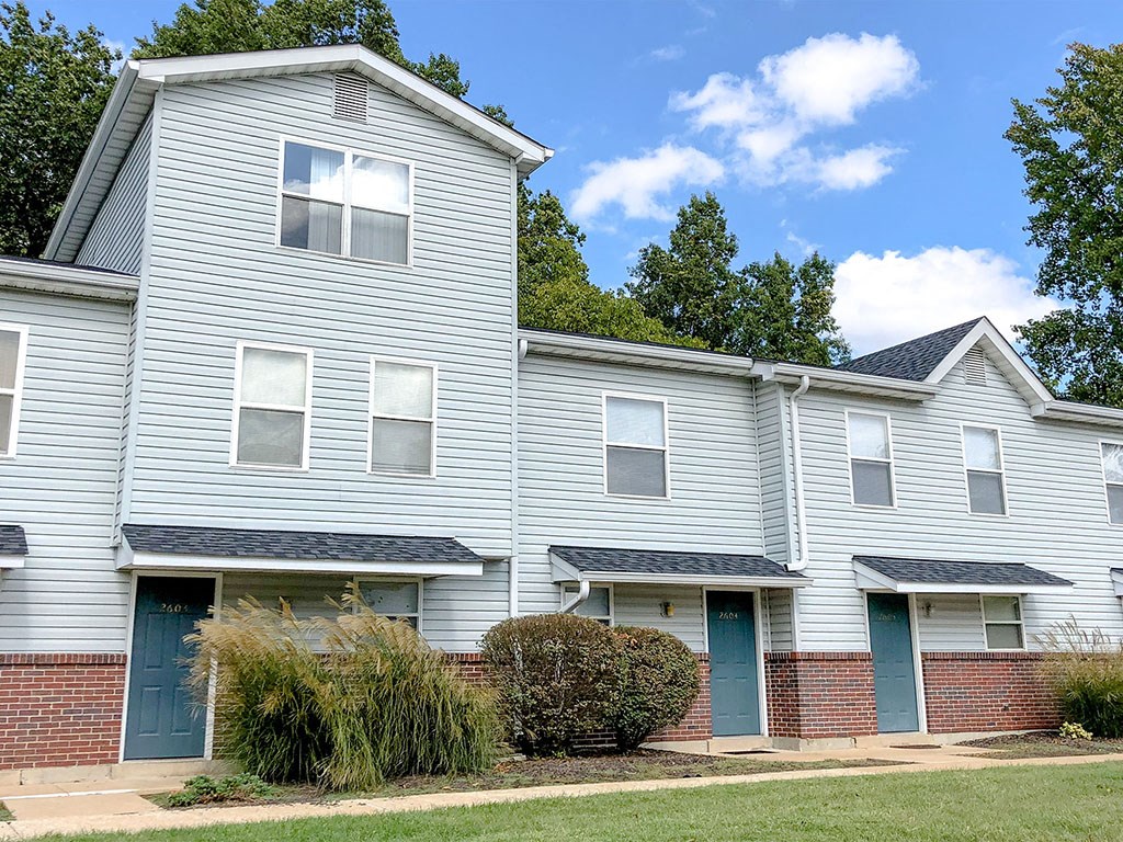 a white house with blue doors and a brick sidewalk