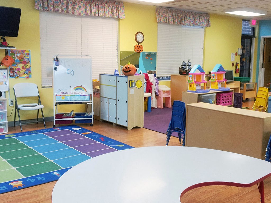 a preschool classroom with a table and chairs and desks and toys