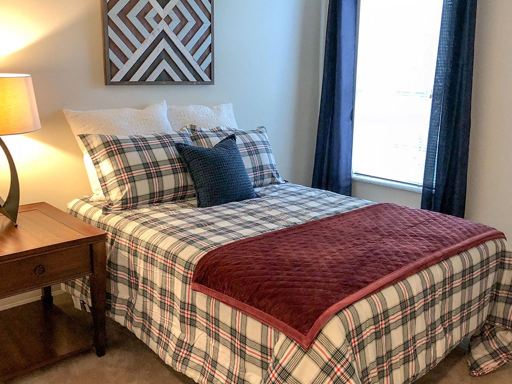 a bedroom with a bed with a plaid comforter