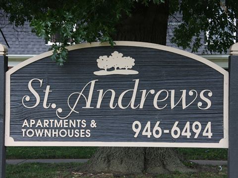 a sign apartments and townhouses in front of a tree