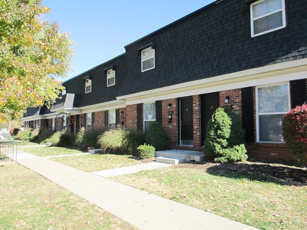 a brick house with a sidewalk in front of it