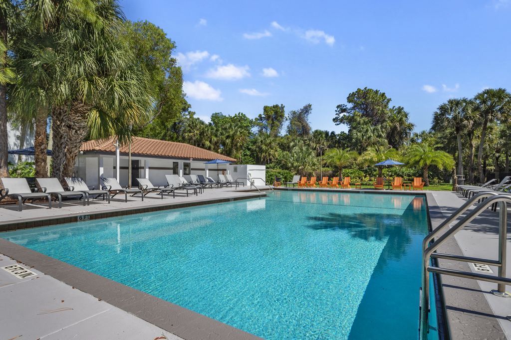 Pool surrounded by lounge chairs and trees