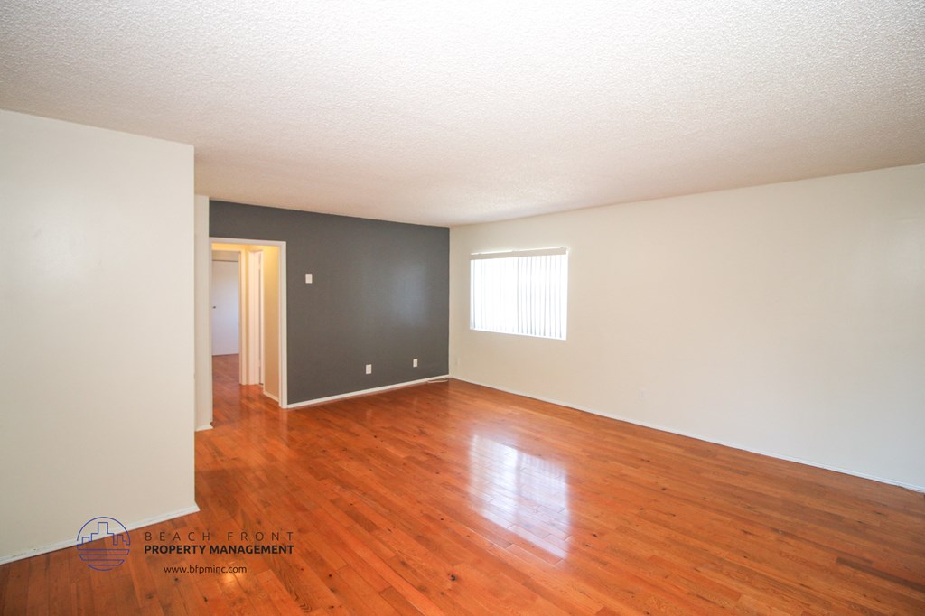 an empty living room with wood floors and a black accent wall