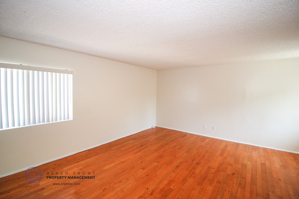 a bedroom with wood floors and white walls and a window
