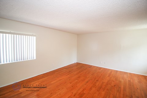 a bedroom with wood floors and white walls and a window