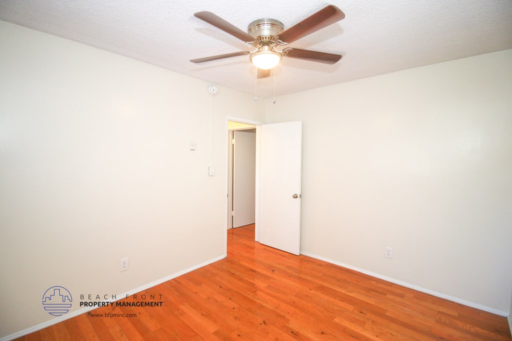 a bedroom with wood floors and a ceiling fan