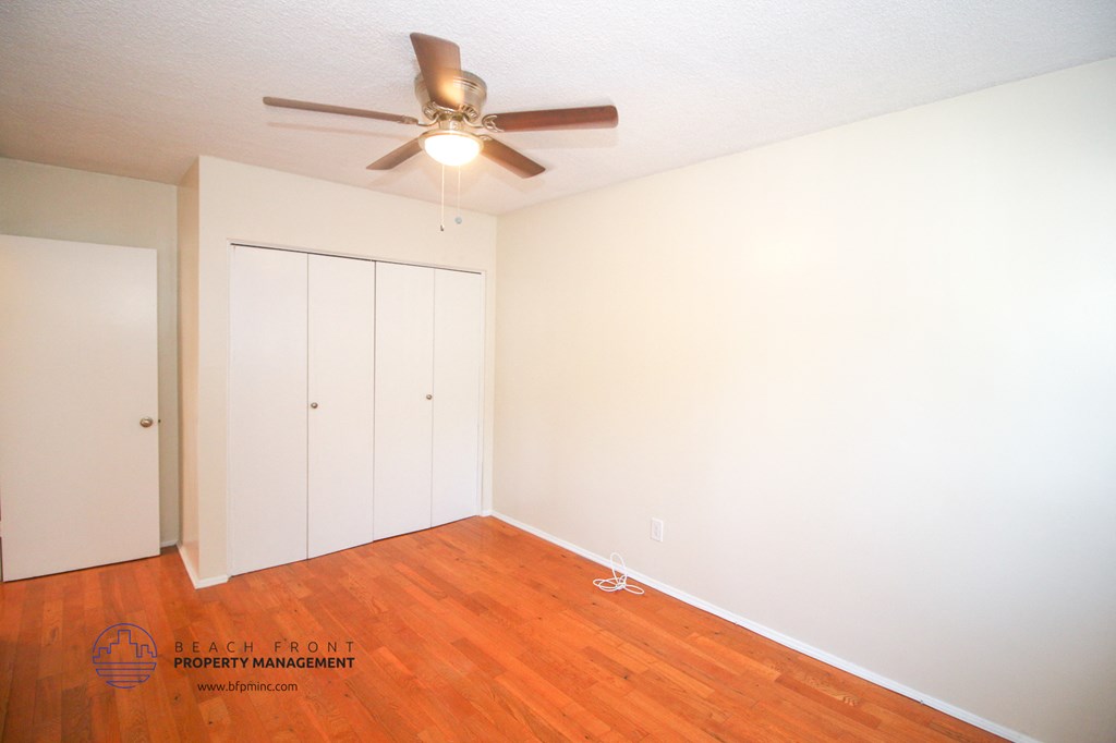 a bedroom with wood flooring and a ceiling fan