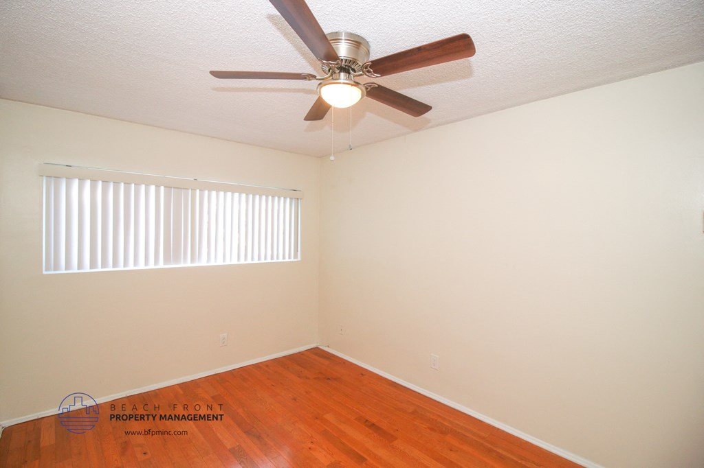 a bedroom with hardwood flooring and a ceiling fan