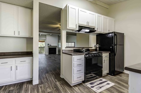 A kitchen with black appliances and white cabinets.