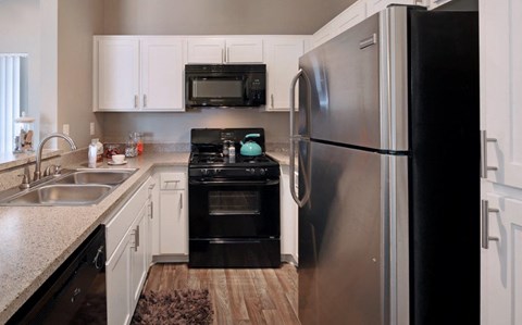 A modern kitchen with a black refrigerator and stove.