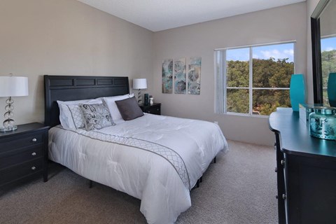 A bedroom with a large bed and a window overlooking a forest.