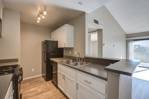 A kitchen with a black refrigerator and white cabinets.