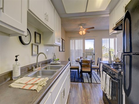 A kitchen with a black refrigerator and a dining table with chairs.