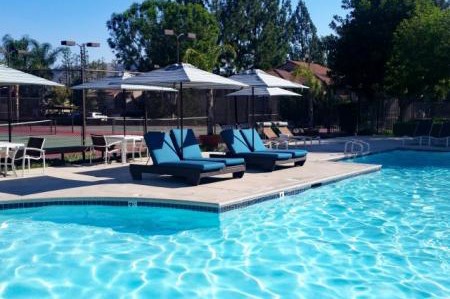 A pool with a blue tinted water and a white umbrella.