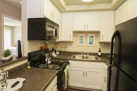 A black stove top oven sits in a kitchen with white cabinets.