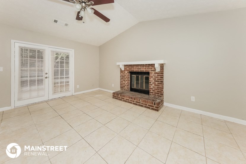 the living room has a brick fireplace and tile flooring