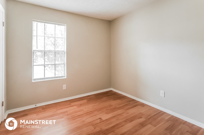 the interior of an empty room with wood flooring and a window