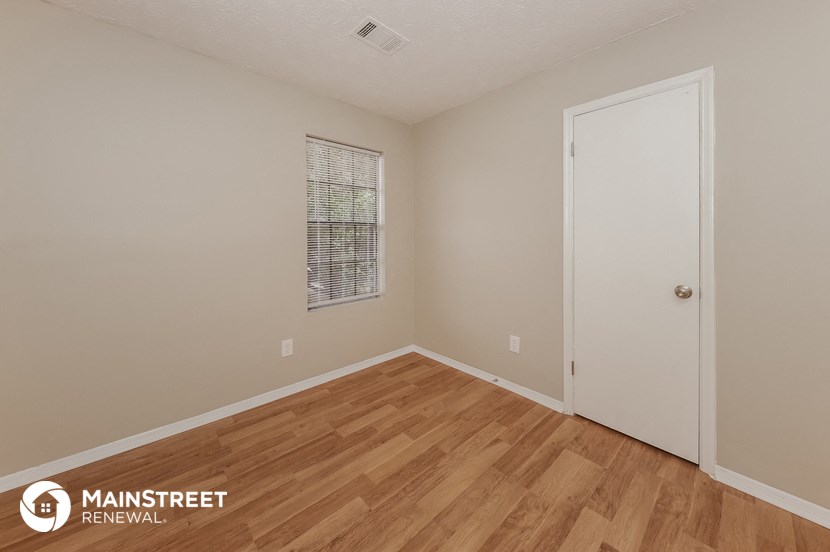 the spacious living room with hardwood flooring and a door to the bedroom