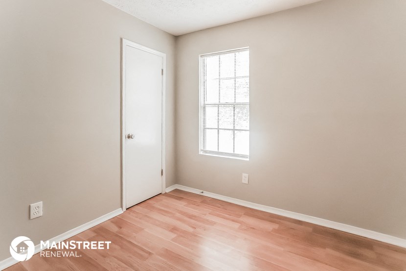 a bedroom with wood flooring and a door to a closet