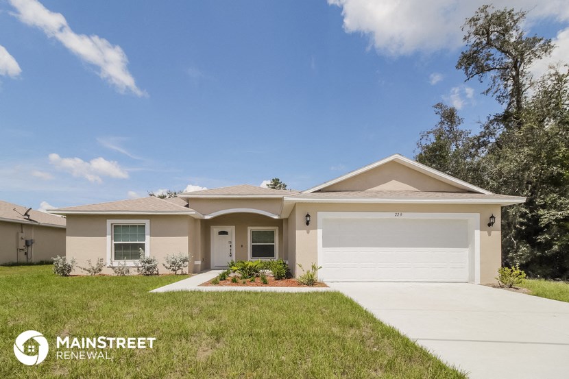 a beige house with a garage door and a lawn