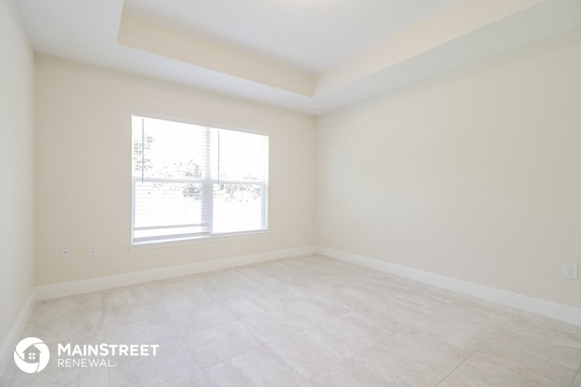 the spacious living room with a large window and tiled floors